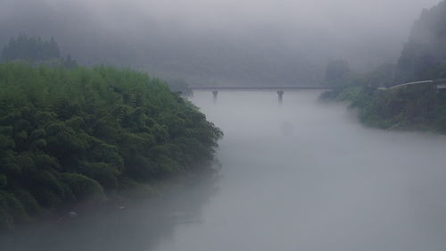 Scenic view of river against sky during foggy weather