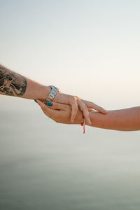 Cropped hand of woman holding hands against white background