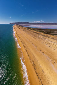 Aerial view of sand spit between clear azure sea and pink lake with salt