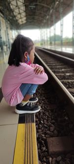 Side view of young woman standing by railing