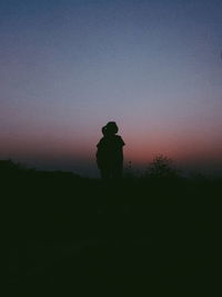 Silhouette man standing on field against sky during sunset