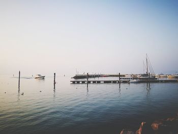 Sailboats moored in sea against clear sky