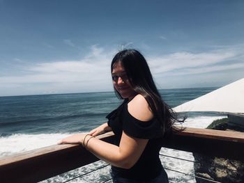 Portrait of smiling young woman on pier by sea 