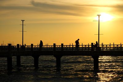 Silhouette pier over sea against sky during sunset