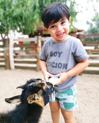 Portrait of cute boy feeding milk to goat 