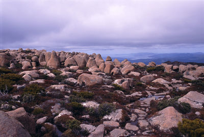 Rocks on mountains against cloudy sky