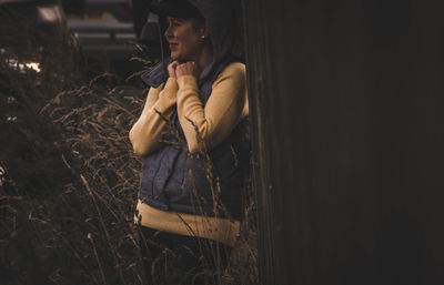 Smiling woman wearing warm clothing while standing amidst plants