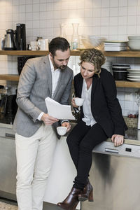 Business people having coffee while reading document at kitchen counter