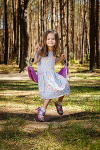 Portrait of girl sitting on swing in playground