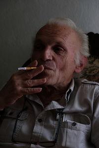 Portrait of senior man smoking cigarette at home