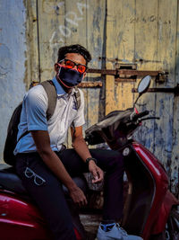 Boy wearing mask sitting on scooter outdoors