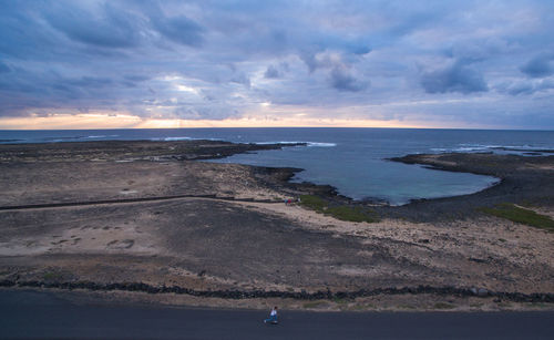 High angle view of woman skating on road by sea against cloudy sky