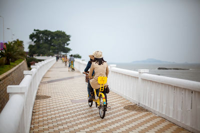 Women riding bicycle on walkway