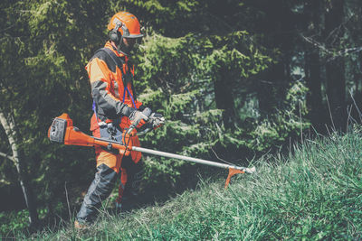 Man holding a brush cutter cut grass. lumberjack at work gardener working outdoor in the forest. 