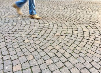 Low section of man walking on cobblestone street