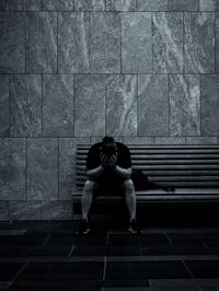 Full length portrait sad man sitting against wall