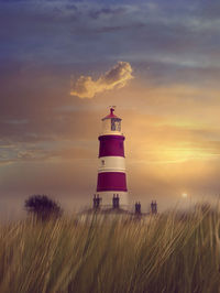 Lighthouse by sea against sky during sunset