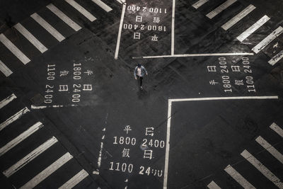 High angle view of man walking on crossroad in city