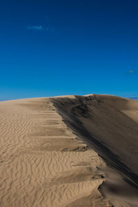 Scenic view of desert against blue sky