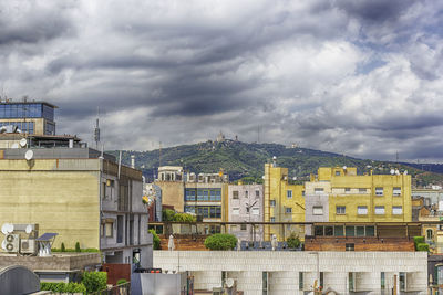 Buildings in city against cloudy sky