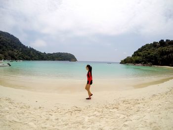 Side view full length of woman at beach against sky