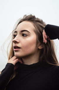 Beautiful young woman with hand on chin looking away
