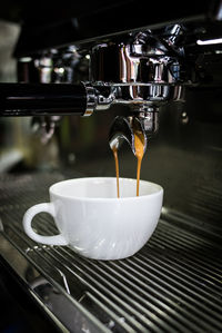 Close-up of coffee cup on espresso maker in cafe