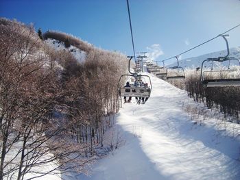 Ski lift on snow covered landscape against sky