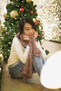 Portrait of young woman with christmas tree at home