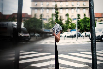 Cropped image of woman by glass building in city