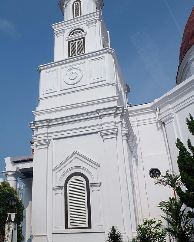 architecture, building exterior, built structure, low angle view, church, religion, place of worship, spirituality, tower, clock tower, tree, sky, blue, sunlight, day, cathedral, clock, cross