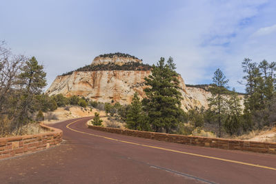 Road by rock formation against sky