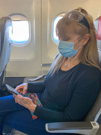 Side view of woman wearing mask sitting in airplane