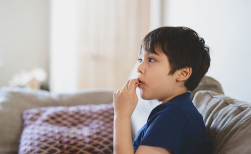 Portrait of boy looking away while sitting at home