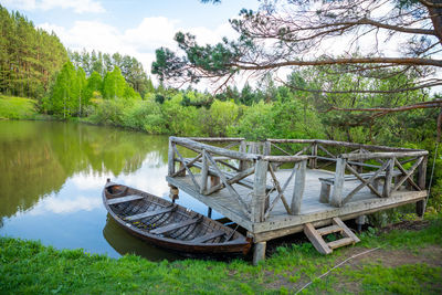 Boat moored on shore by lake against sky