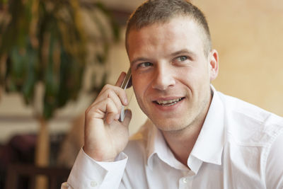 Businessman answering smart phone in office