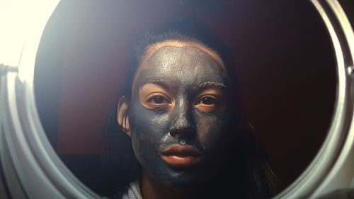 Woman with mud mask reflecting on mirror