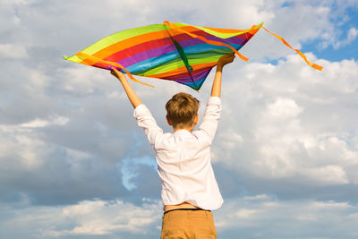 Rear view of woman holding umbrella against sky