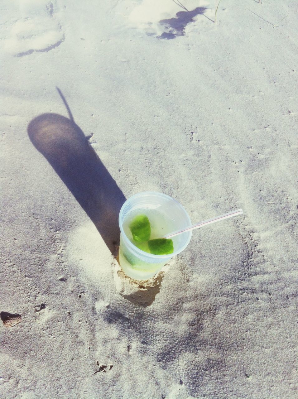 drink, refreshment, food and drink, high angle view, still life, sand, freshness, close-up, beach, day, drinking glass, coffee cup, shadow, table, sunlight, single object, bottle, coffee - drink, outdoors, directly above