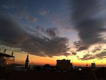 Silhouette buildings against cloudy sky during sunset