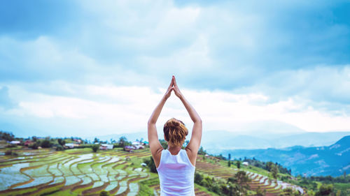 Rear view of woman standing on field against sky