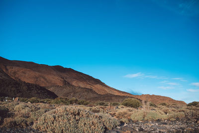 Scenic view of landscape and mountains against blue sky