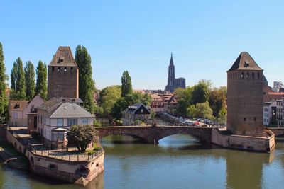 Bridge over river by buildings against sky