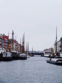 Sailboats moored at harbor against clear sky