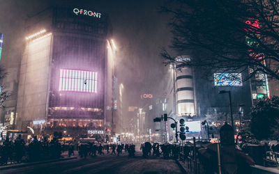 People crossing street in illuminated city at night