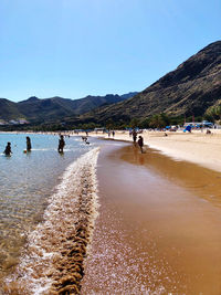 People on beach against clear sky