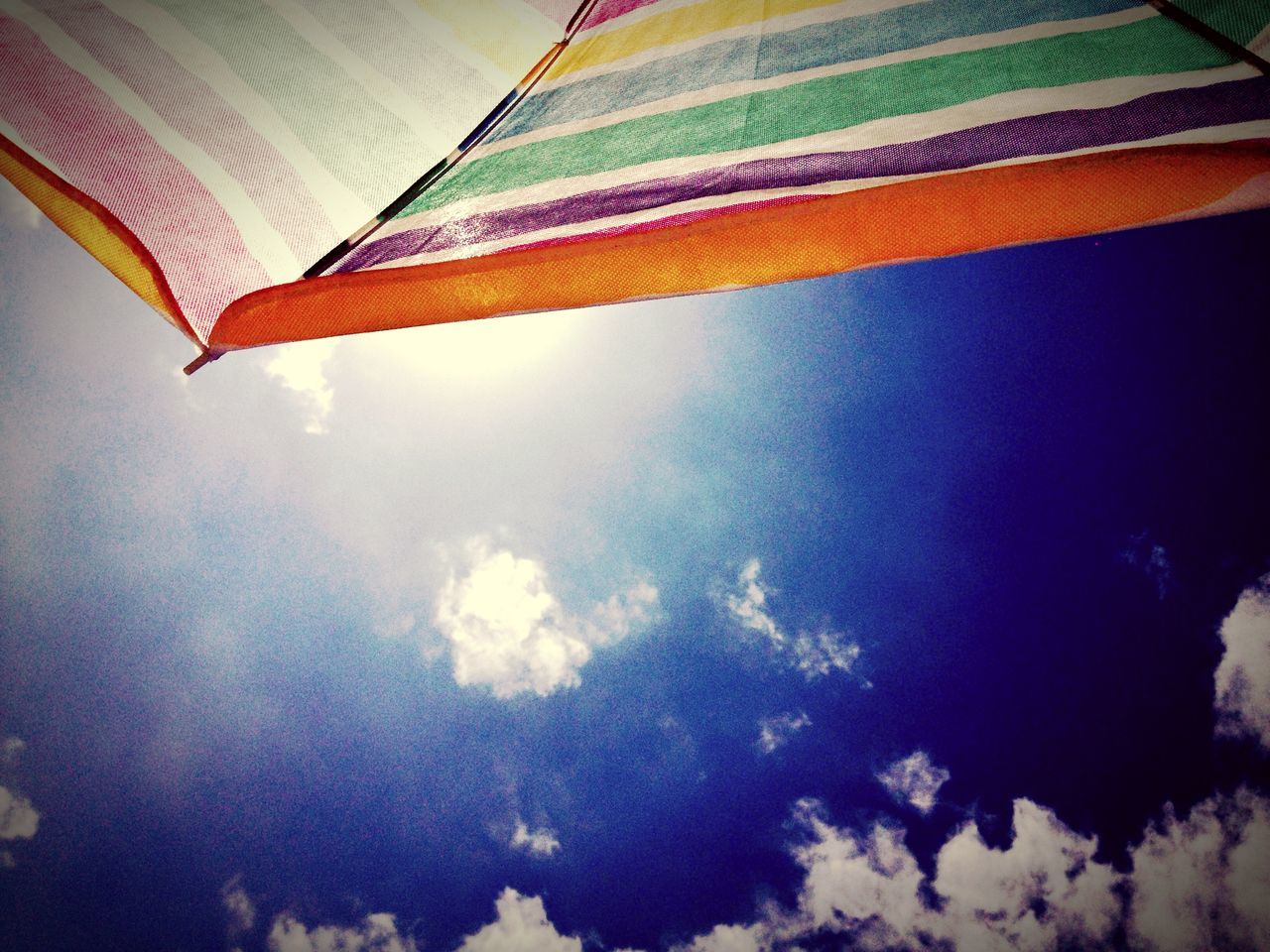 low angle view, sky, multi colored, no people, outdoors, nature, built structure, architecture, day, building exterior, beauty in nature, leaf, cloud - sky, roof, cloud, flag, palm tree, colorful, orange color, sunlight