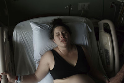 High angle view of painful pregnant woman lying on hospital bed