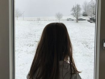 Rear view of woman looking through window