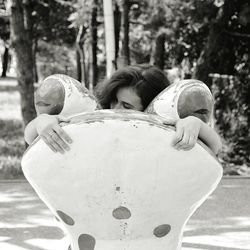 Woman embracing frog structure at park